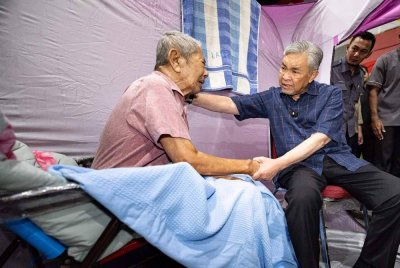 Timbalan Perdana Menteri, Datuk Seri Dr Ahmad Zahid Hamidi bertanya khabar dengan salah seorang mangsa banjir, Mahayuddin Abd Hashim, 84, ketika mengadakan lawatan ke Pusat Pemindahan Sementara (PPS) di Kompleks Umno Bagan Datuk Sungai Sumun hari ini. Foto Bernama 