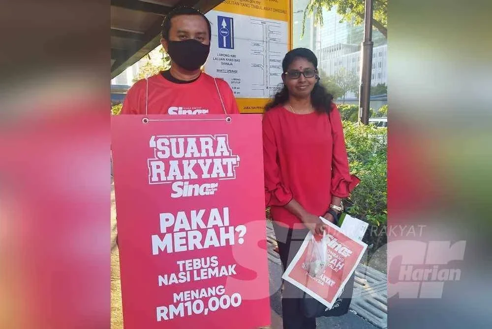 Antara pengguna LRT menerima akhbar Sinar Harian secara percuma di LRT Ampang Park pada Isnin.