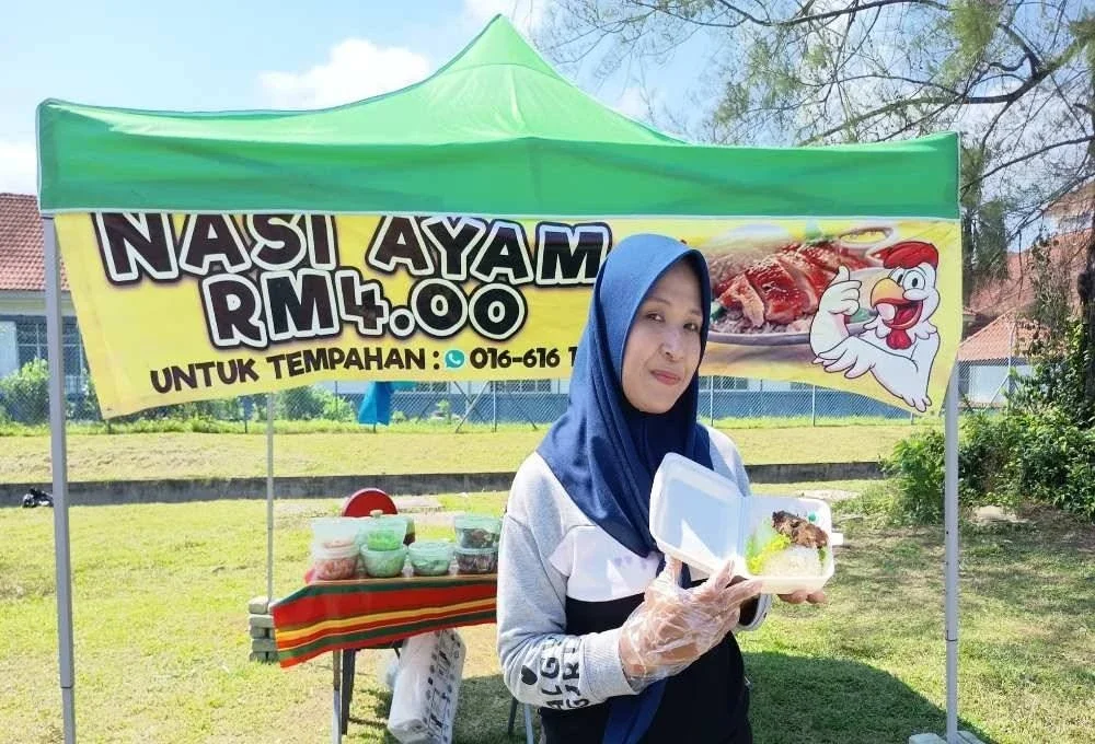 Pekerja gerai jualan nasi ayam, Shazilah Samad, 38 menunjukkan nasi ayam yang dijual pada harga RM4 di Kampung Kubang Badak, Kuala Nerus.