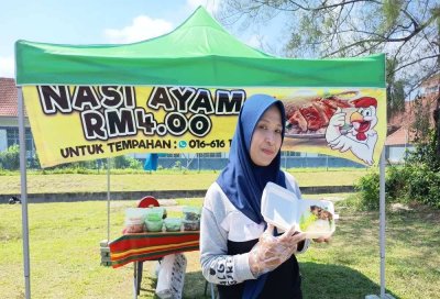 Pekerja gerai jualan nasi ayam, Shazilah Samad, 38 menunjukkan nasi ayam yang dijual pada harga RM4 di Kampung Kubang Badak, Kuala Nerus.