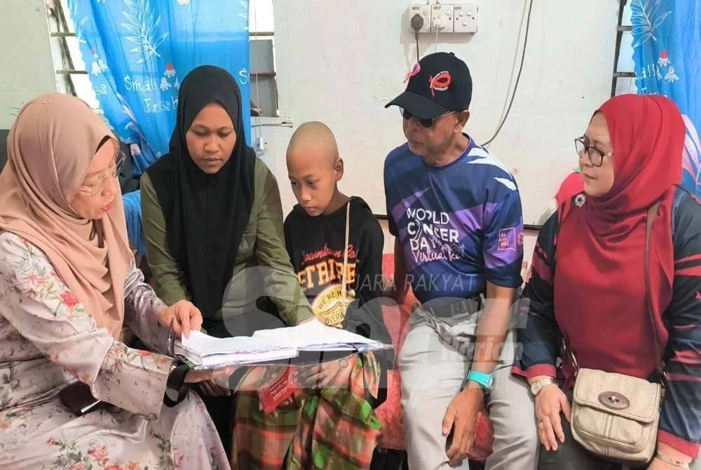 Zuraini (kiri) melihat rekod rawatan Muhammad Qhosiff Basyar semasa melawatnya di Desa KEDA Malau di Jitra pada Rabu.
