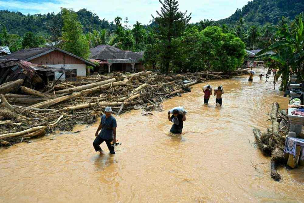 Penduduk menempuh banjir di Kampung Tukka, Tapanuli Tengah, Negeri Sumatera Utara.