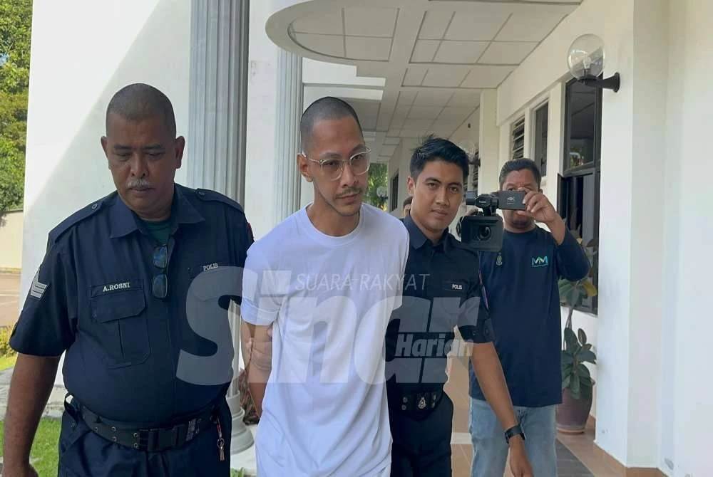 Tertuduh diiringi anggota polis ketika dibawa ke Mahkamah Balik Pulau, pada Khamis.