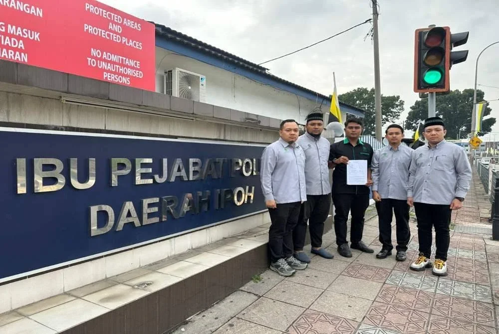 Muhammad Faiz (tengah) menunjukkan laporan polis yang dibuat di IPD Ipoh di sini pada Khamis.