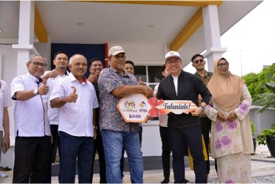 Nga Kor Ming (dua dari kanan) menyerahkan kunci perumahan baharu kepada Mohmad Johar Misri (tiga dari kiri) pada majlis penyerahan kunci kepada mangsa insiden kebakaran gas Putra Heights di Kampung Sungai Baru, Putra Heights hari ini. - Foto: Bernama 