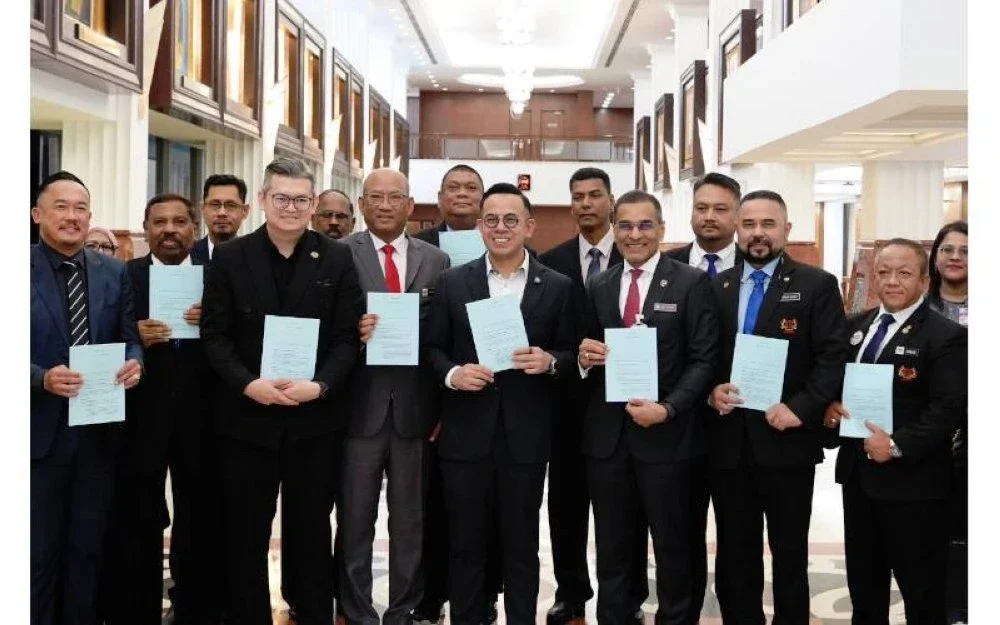 Steven Sim (tengah) mempamerkan RUU Akta Keselamatan Sosial Pekerja 2025 (Pindaan) atau Akta 4 yang diluluskan di Dewan Rakyat pada Selasa.