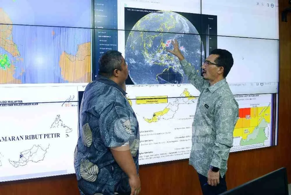 Dr Mohd Hisham (kanan) memberi penerangan kepada Khairil Anwar mengenai sistem model ramalan cuaca yang diguna pakai MET Malaysia. 