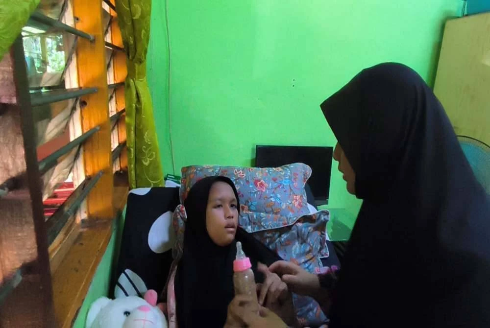 Nur Iman Syamimi minum menggunakan botol susu dan perlu memakai lampin pakai buang sepanjang masa.