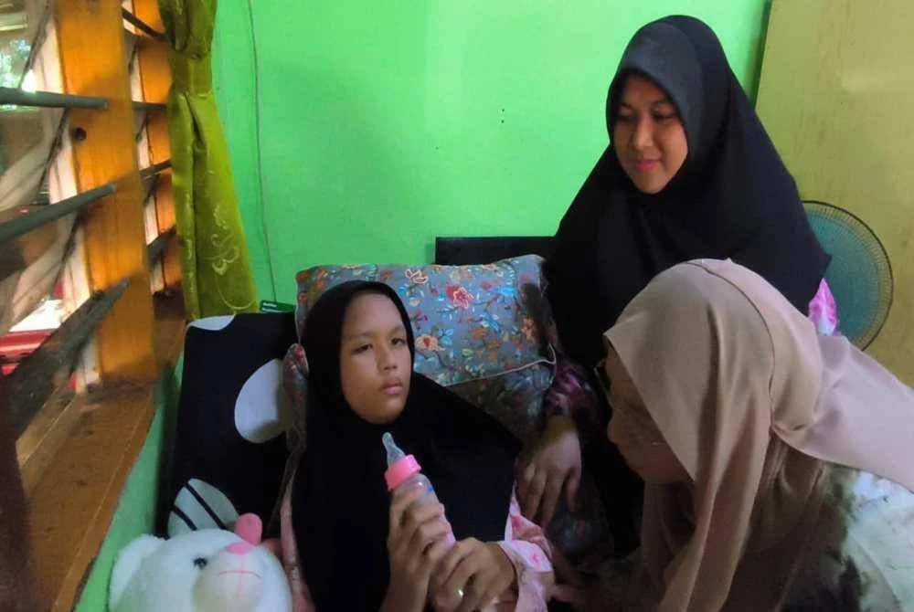 Zuraini (kanan) melihat keadaan Nur Iman Syamimi semasa menziarahinya di Kampung Kepala Bukit, Mukim Padang Perahu, Jitra.