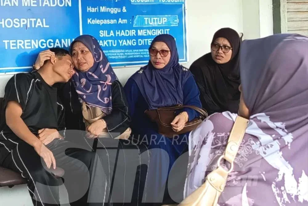 Che Norhashimah (dua dari kiri) menenangkan salah seorang anaknya yang menangis ketika menunggu urusan bedah siasat di Unit Forensik Hospital Hulu Terengganu.