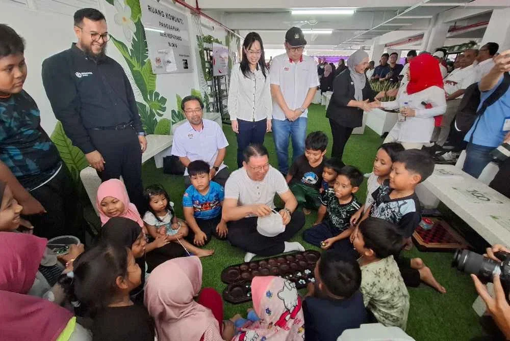 Kor Ming menyantuni kanak-kanak yang menerima manfaat daripada Ruang Komuniti sempena perasmian Rukom ke-100 di PPR Pangsapuri Seri Kepayang pada Sabtu.