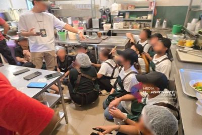 Pengukuatkuasa JIM memeriksa warga asing yang ditahan di salah sebuah premis makanan dalam serbuan tersebut.- foto JIM Johor