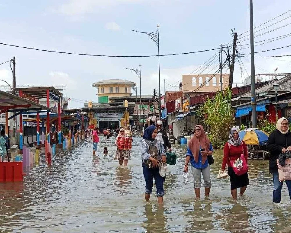Orang ramai meredah air pasang dari terminal feri Kukup.