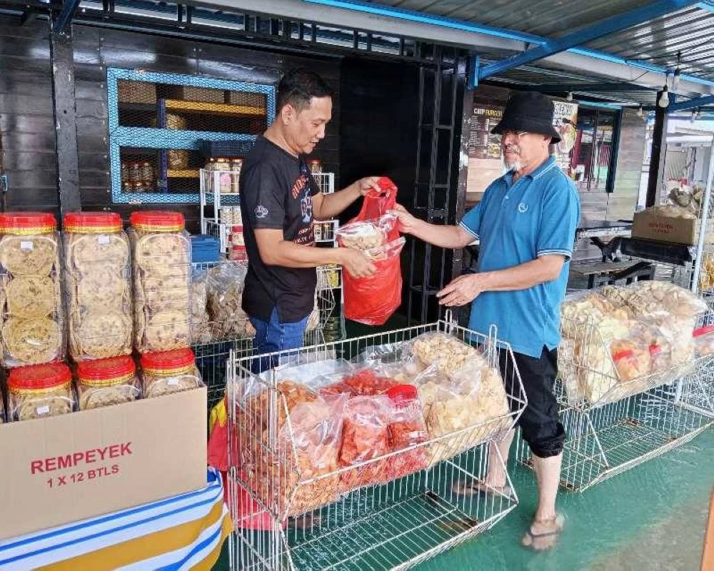 Zulkifli (kiri) berniaga ketika air pasang besar melanda Pekan Kukup.