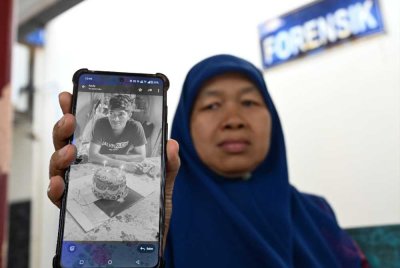 Norihan Mohd Noor, 58, menunjukkan gambar anaknya Allahyarham Muhammad Anuar Syurkimie ketika ditemui pemberita di Unit Forensik Hospital Kemaman pada Ahad. Foto Bernama
