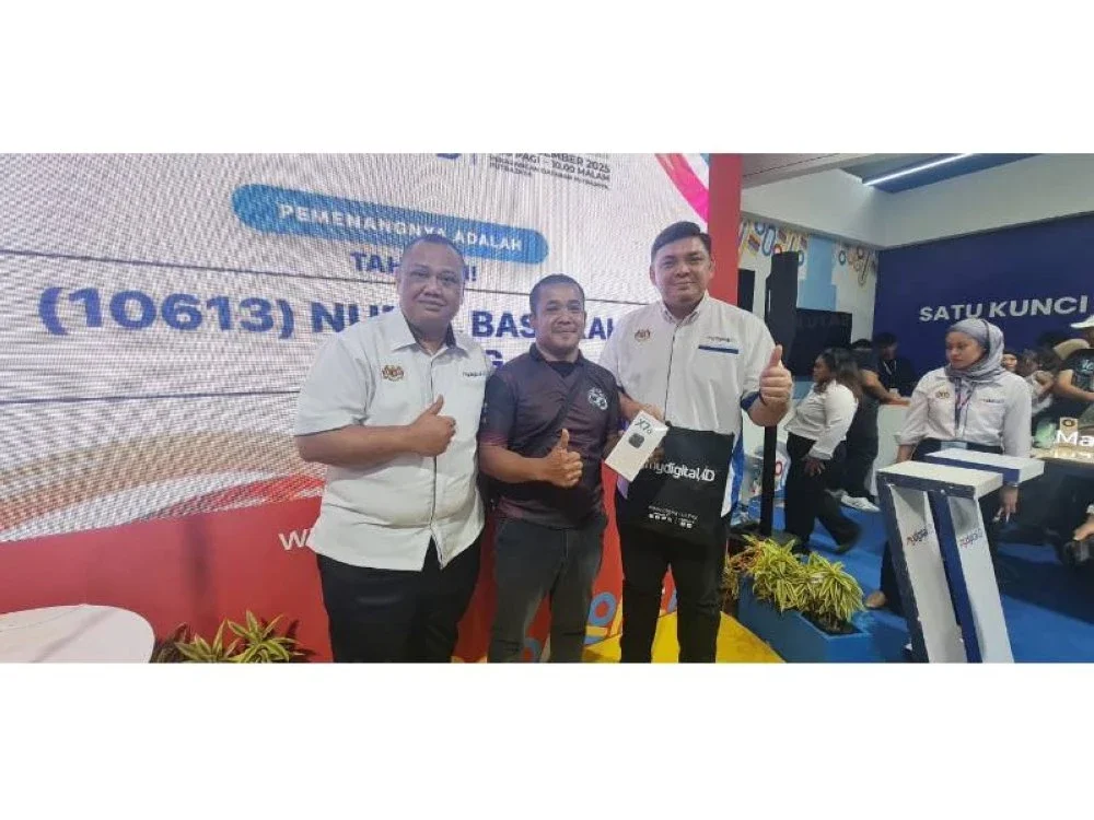 Ketua Pegawai Operasi MyDigital ID, Mohd Azuddin Parman (kiri) dan Ketua Pegawai Komersial MyDigital ID, Mohamad Sany Yahaya bersama Shazian Shukri Mat Lud (tengah) pemenang tempat ketujuh pada sesi cabutan di reruai MyDigital ID pada Ahad.