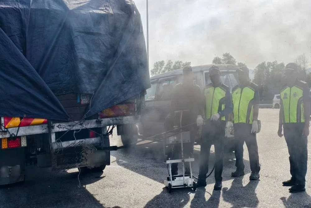 Anggota penguat kuasa JAS Negeri Sembilan memeriksa asap sebuah lori. 