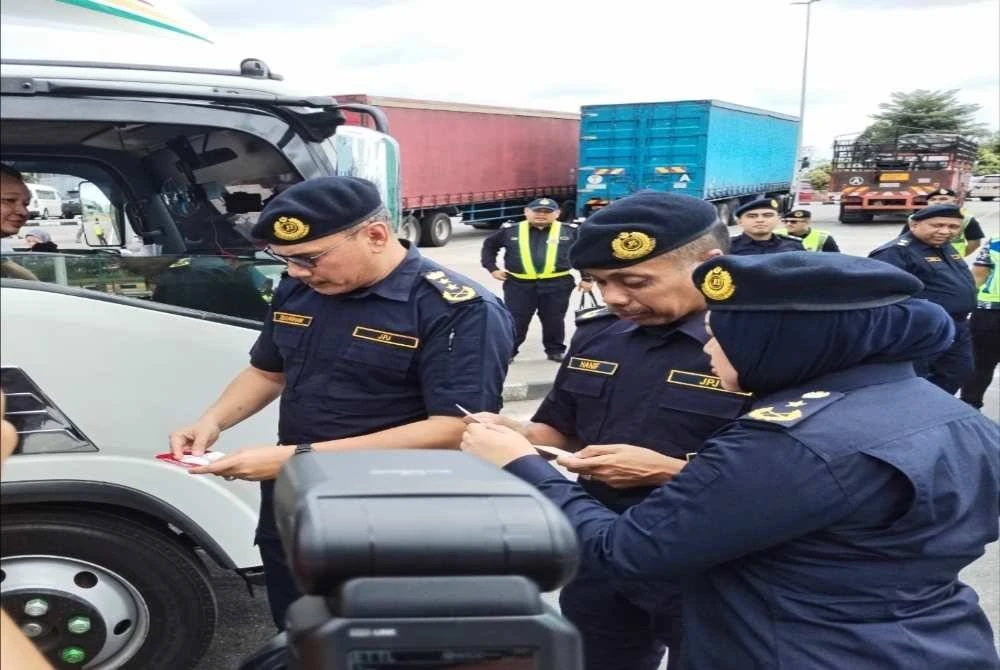 Zulkarnain (kiri), Hanif Yusabra dan Siti Zarina memeriksa dokumen salah sebuah kenderaan pada operasi berkenaan.