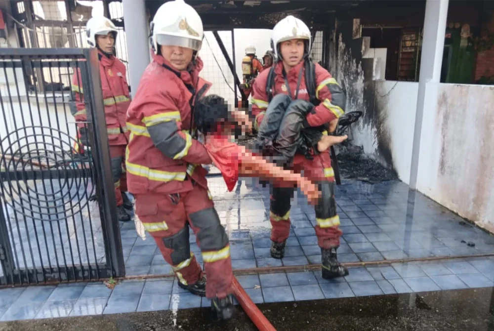Pasukan bomba menyelamatkan seorang mangsa yang cedera dalam kebakaran sebuah rumah di di Lorong Nakhoda 5, Taman Rathna, Butterworth pada pagi Rabu.