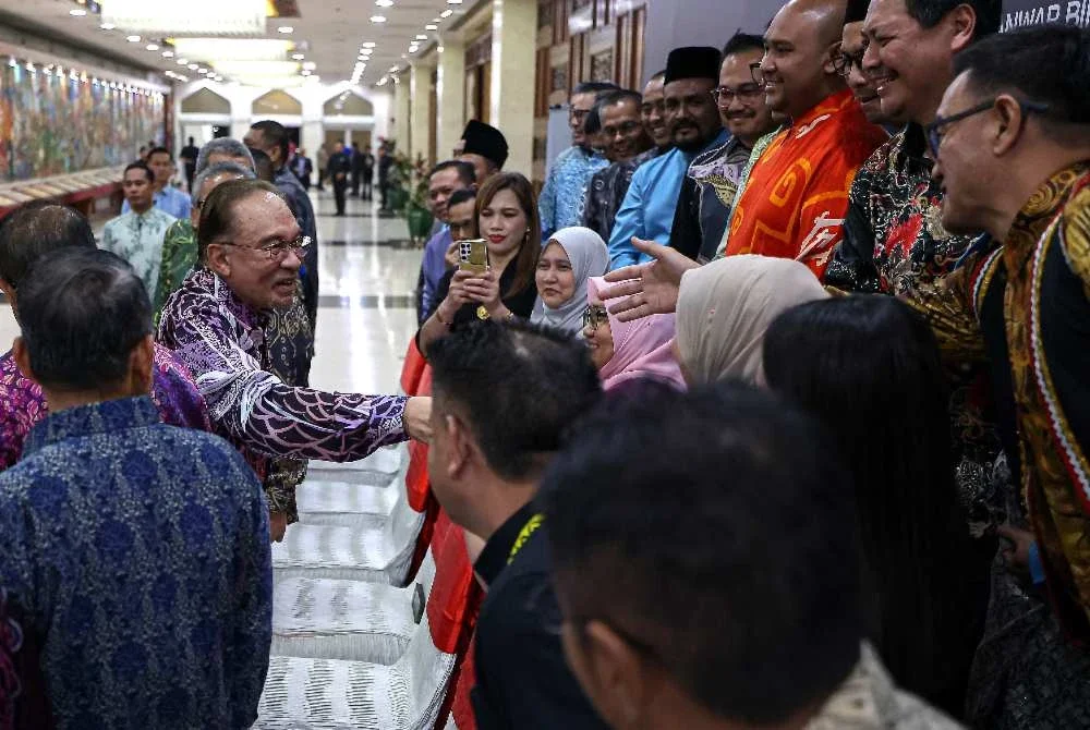 Anwar (kiri) beramah mesra dengan orang ramai ketika hadir pada Majlis Makan Malam sempena Konvensyen Kongress Tritahunan Cuepacs ke-30 di Pusat Dagangan Dunia Kuala Lumpur pada Rabu. Foto: Bernama 