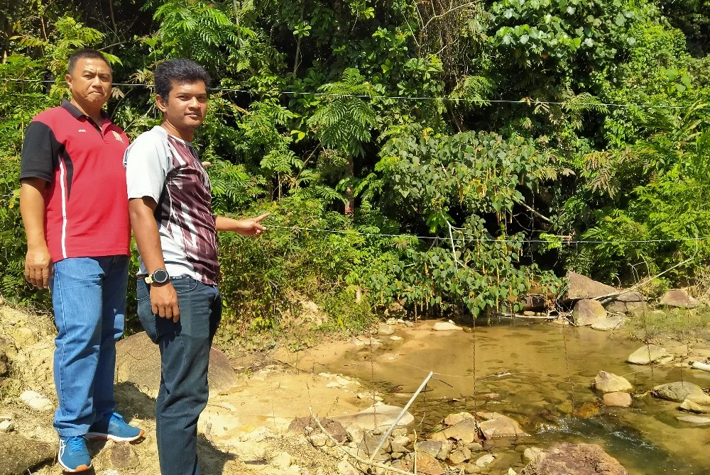 Muhammad Kamarulzaman (kanan) bersama Khairuddin menunjukkan antara laluan gajah ke kawasan ladang peneroka.