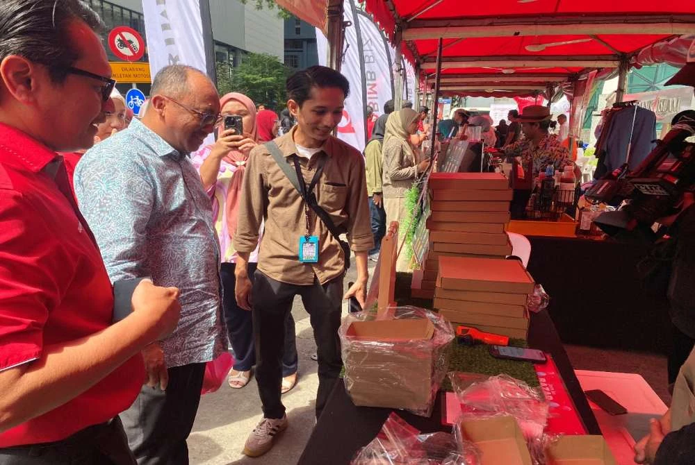 Mizan (tengah) melawat gerai jualan di bazar yang dibuka khas selama tiga hari sempena pelancaran ciri Payment to Voice dalam aplikasi BIMB.