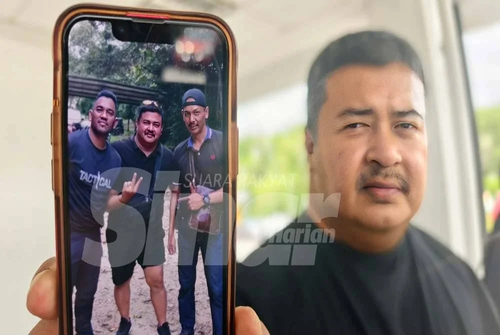 Nizam menunjukkan gambar kenangannya bersama Allahyarham (kanan) Azrul Fariz Kamarul Baharin, yang maut akibat ditembak. 