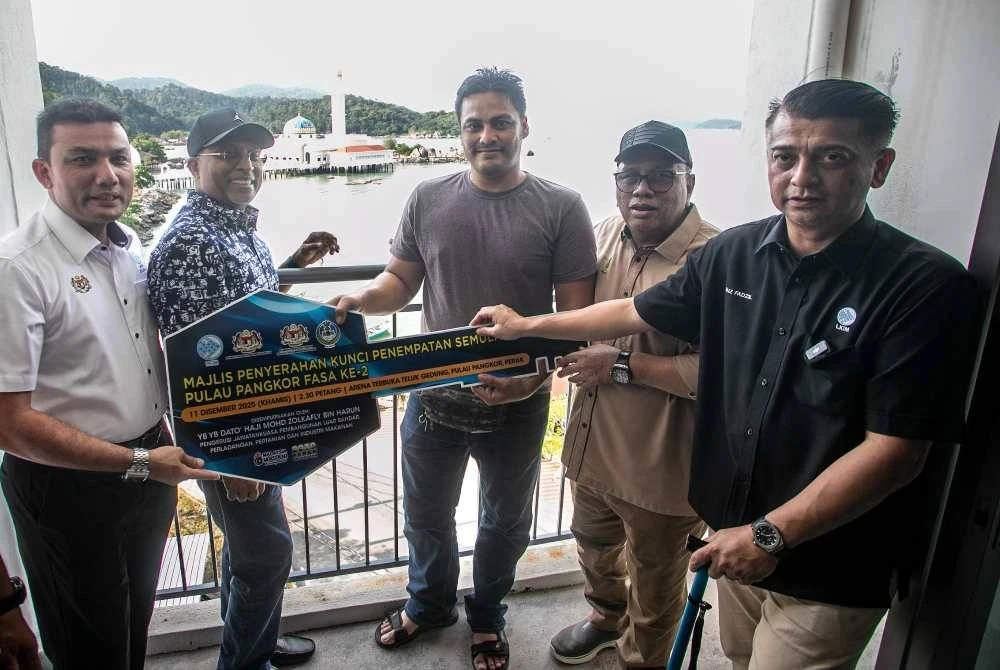 Muhamad Asri (tengah) menerima kunci unit rumah di bawah projek PSN Pulau Pangkor fasa kedua yang melibatkan peruntukan keseluruhan RM16 juta.
