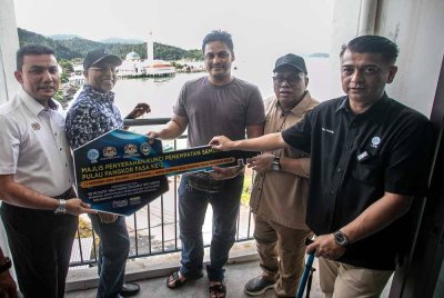 Muhamad Asri (tengah) menerima kunci unit rumah di bawah projek PSN Pulau Pangkor fasa kedua yang melibatkan peruntukan keseluruhan RM16 juta.