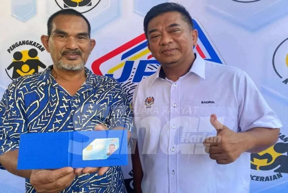 Shaharuddin (kiri) menerima penyerahakan kad pengenalan yang disampaikan oleh Badrul Hisham di rumahnya di Kampung Keting, Gunong, Bachok pada Jumaat.FOTO: SINAR HARIAN/HAZELEN LIANA KAMARUDIN