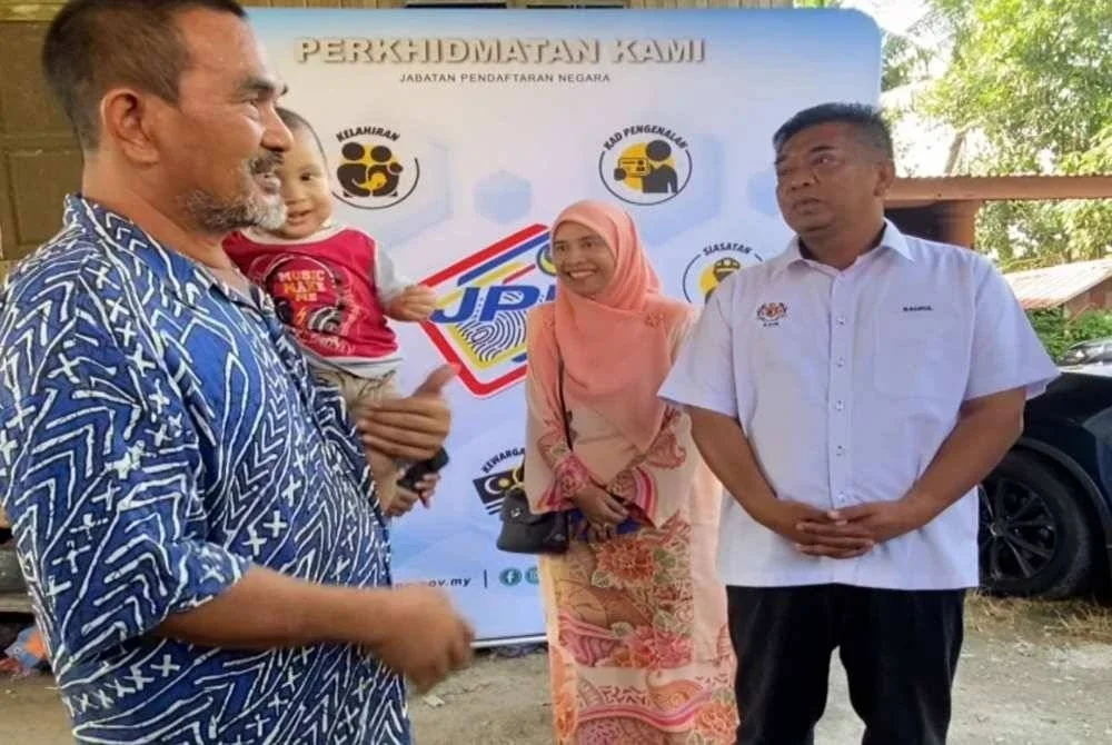 Badrul Hisham (kanan) beramah mesra selepas menyerahkan MyKad kepada Shaharuddin di rumahnya di Kampung Keting, Gunong, Bachok pada Jumaat.