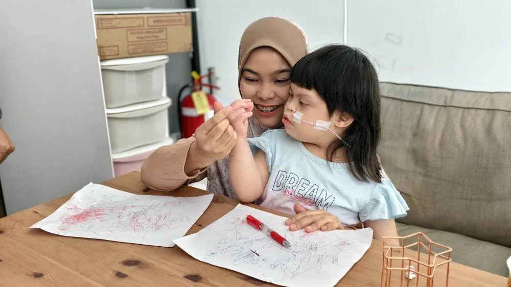 Seorang ibu membawa anaknya menjalani sesi terapi di Bilik Terapi Sensori Ronald McDonald di Tampin.