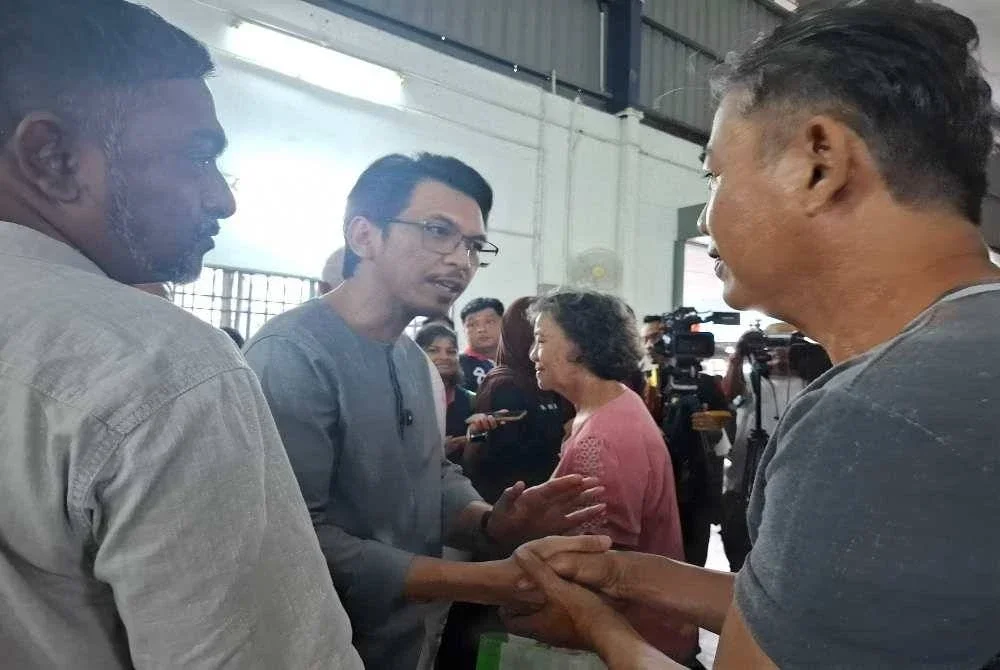 Muhammad Kamil (tengah) menyatuni wakil petani yang hadir dalam pertemuan khas di Dewan Orang Ramai Kampung Baru Kuala Kuang pada Jumaat.
