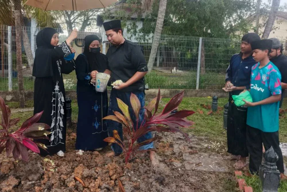 Ezlyn Ilyana (dua dari kiri) bersama adik-adiknya menyiram air mawar di pusara ibu mereka didi Tanah Perkuburan Islam Suka Menanti, Alor Setar selepas solat Asar pada Jumaat.
