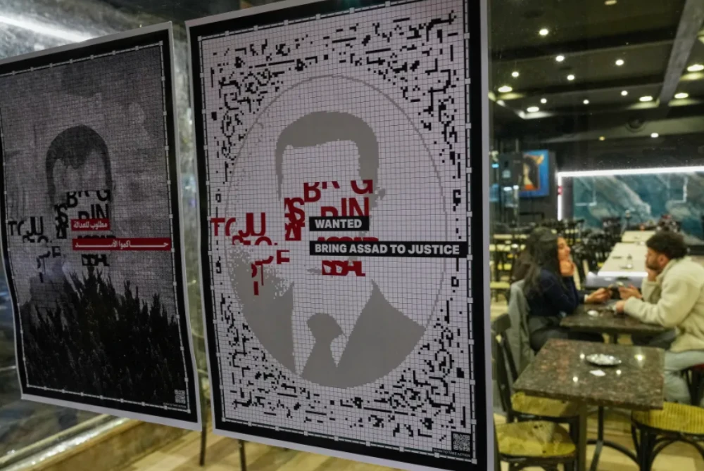 Potret al-Assad tertera 'orang dikehendaki' dan bawa ke muka pengadilan ditampal di luar sebuah kafe di ibu kota.