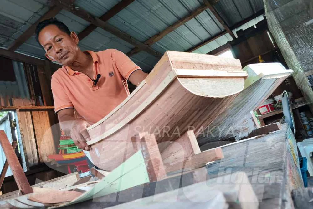 Engku Abbas menunjukkan replika bot patak itik yang sedang disiapkan di bengkel kecilnya di Kuala Besut, hasil buatan tangan yang mengekalkan keaslian seni pertukangan tradisi Terengganu.