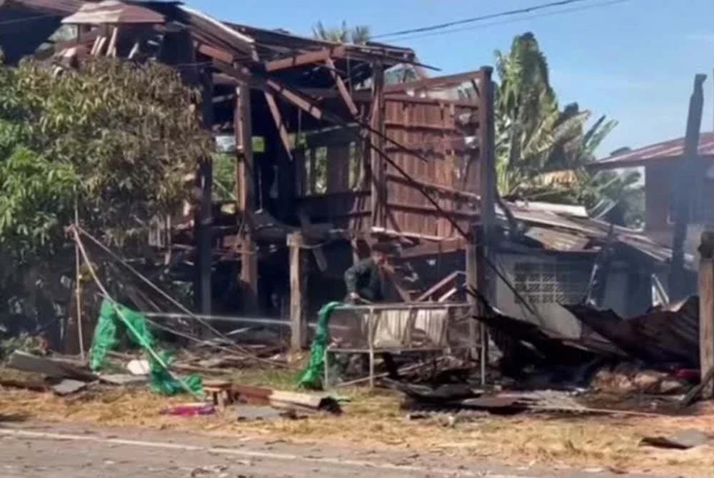 Sebuah rumah terbakar akibat serangan sementara anggota bomba menyembur air dan mengeluarkan tong gas dari kediaman yang hangus. Foto Reuters