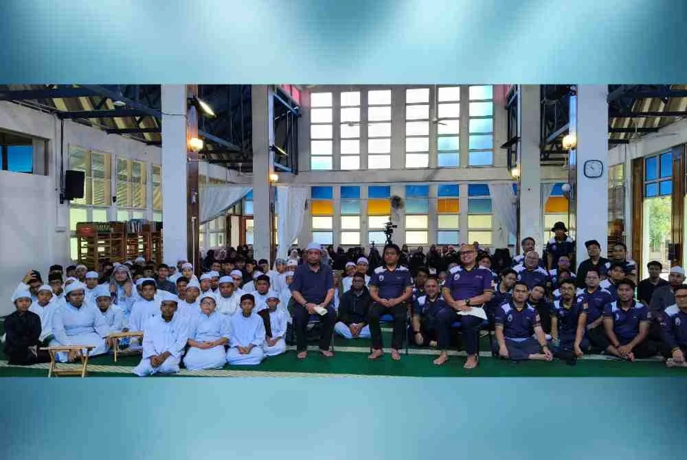 Duduk di kerusi, Dr Mohd Nizam (tengah), Hafiz (kiri) dan Muhammad Ezra bergambar bersama pasukan dari UniKL MIIT serta pelajar Maahad An-Noer.