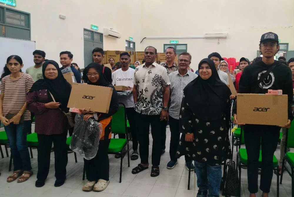 Saravanan (tengah) bersama penerima sumbangan komputer riba selepas majlis penyampaian di Pejabat MIC Bahagian Tapah pada Ahad.