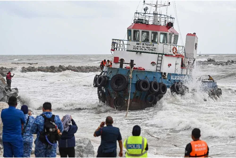 Anggota penyelamat membantu menyelamatkan kru bot yang terperangkap di dalam bot tunda yang terdampar di sekitar kawasan pembinaan benteng pemecah ombak di Pantai Batu Rakit, hari ini. - Foto: Bernama