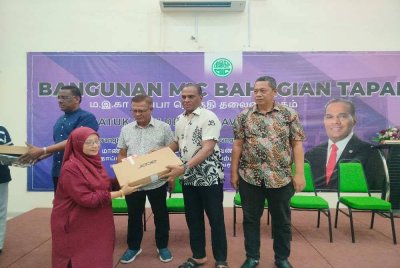 Saravanan (dua dari kanan) menyerahkan komputer riba kepada penerima di Pejabat MIC Bahagian Tapah di sini pada Ahad.