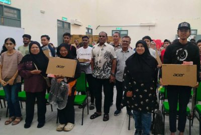 Saravanan (tengah) bersama penerima sumbangan komputer riba selepas majlis penyampaian di Pejabat MIC Bahagian Tapah pada Ahad.