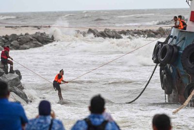 Anggota penyelamat membantu menyelamatkan kru bot yang terperangkap di dalam bot tunda yang terdampar di sekitar kawasan pembinaan benteng pemecah ombak di Pantai Batu Rakit, hari ini. - Foto: Bernama