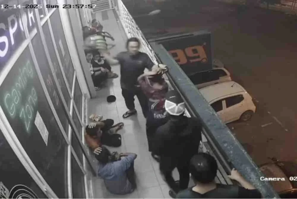 Tangkap layar video tular memaparkan seorang lelaki memukul salah seorang remaja menggunakan topi keledar di kawasan premis di Kota Kinabalu.