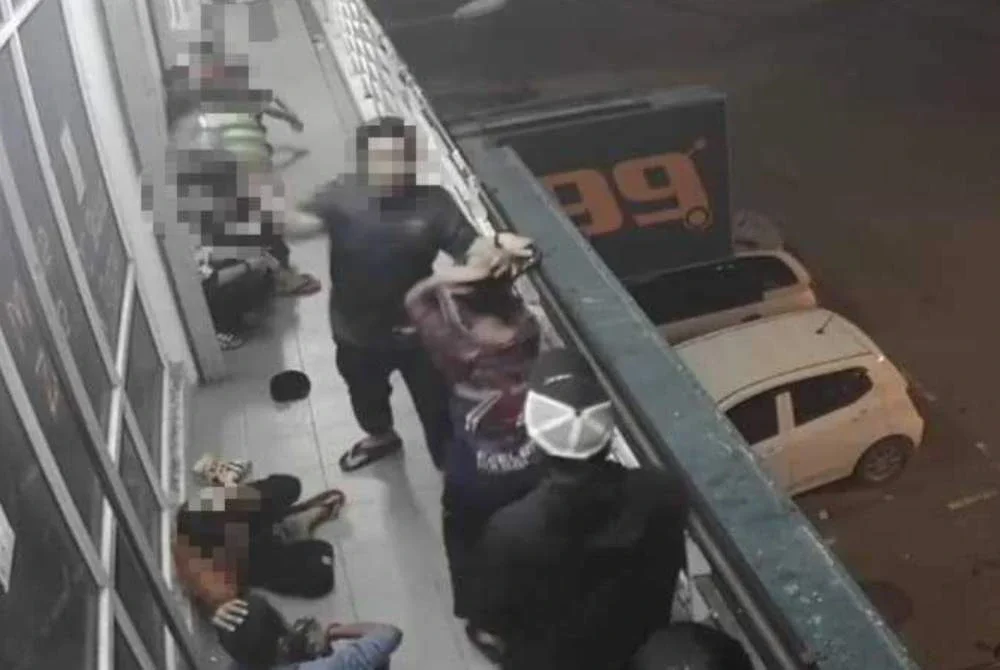 Tangkap layar video tular memaparkan seorang lelaki memukul salah seorang remaja menggunakan topi keledar di kawasan premis di Kota Kinabalu.