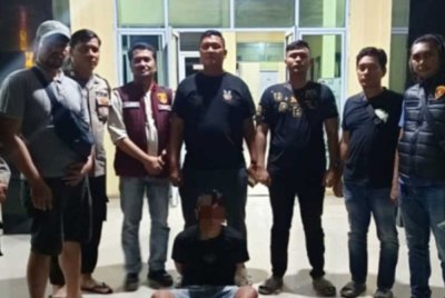 Suspek (duduk) ketika ditahan polis. - Agensi