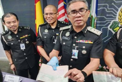 Khairrul Aminus (kanan) menunjukkan pasport yang dirampas dalam serbuan dijalankan.