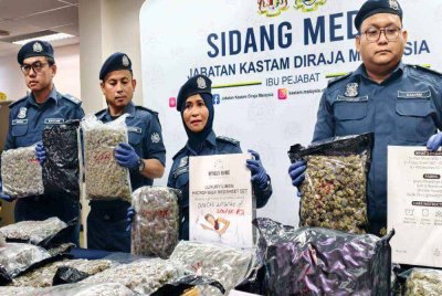 Siti (tengah) menunjukkan kotak digunakan untuk membungkus bunga ganja dalam serbuan tersebut.