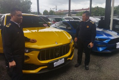 Aedy Fadly (kiri) melihat kenderaan mewah yang disita.