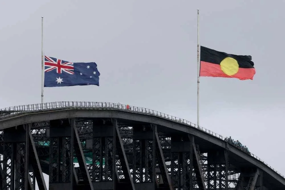 Bendera Australia dan Bendera Orang Asal Australia dikibarkan separuh tiang di Jambatan Sydney Harbour susulan insiden tembakan di Pantai Bondi. Foto AFP